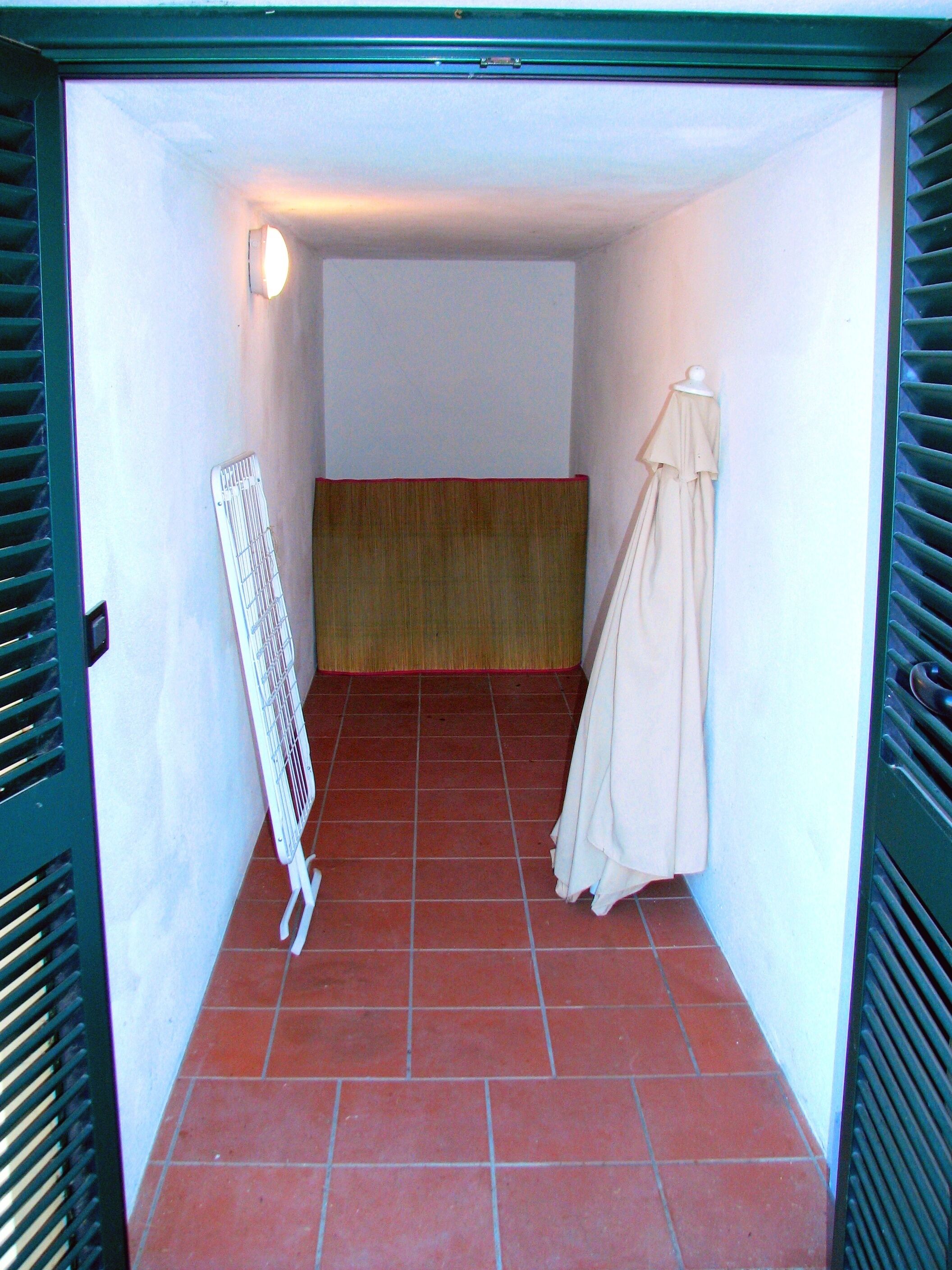 Ein schmaler Flur mit Fliesenboden, einem Heizkörper und einer mit heller Kleidung ausgestatteten Schaufensterpuppe.