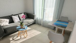 A modern living room with a grey sofa, a small round table with a blue top, and a white chair. - VILLA SOLARIS Independent studio in villa with pool (Alpes-Maritimes)