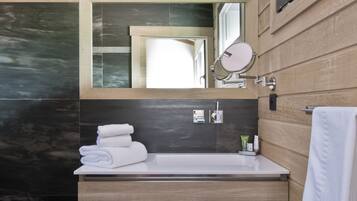 A modern bathroom with a wooden vanity, a large mirror, and a towel rack.