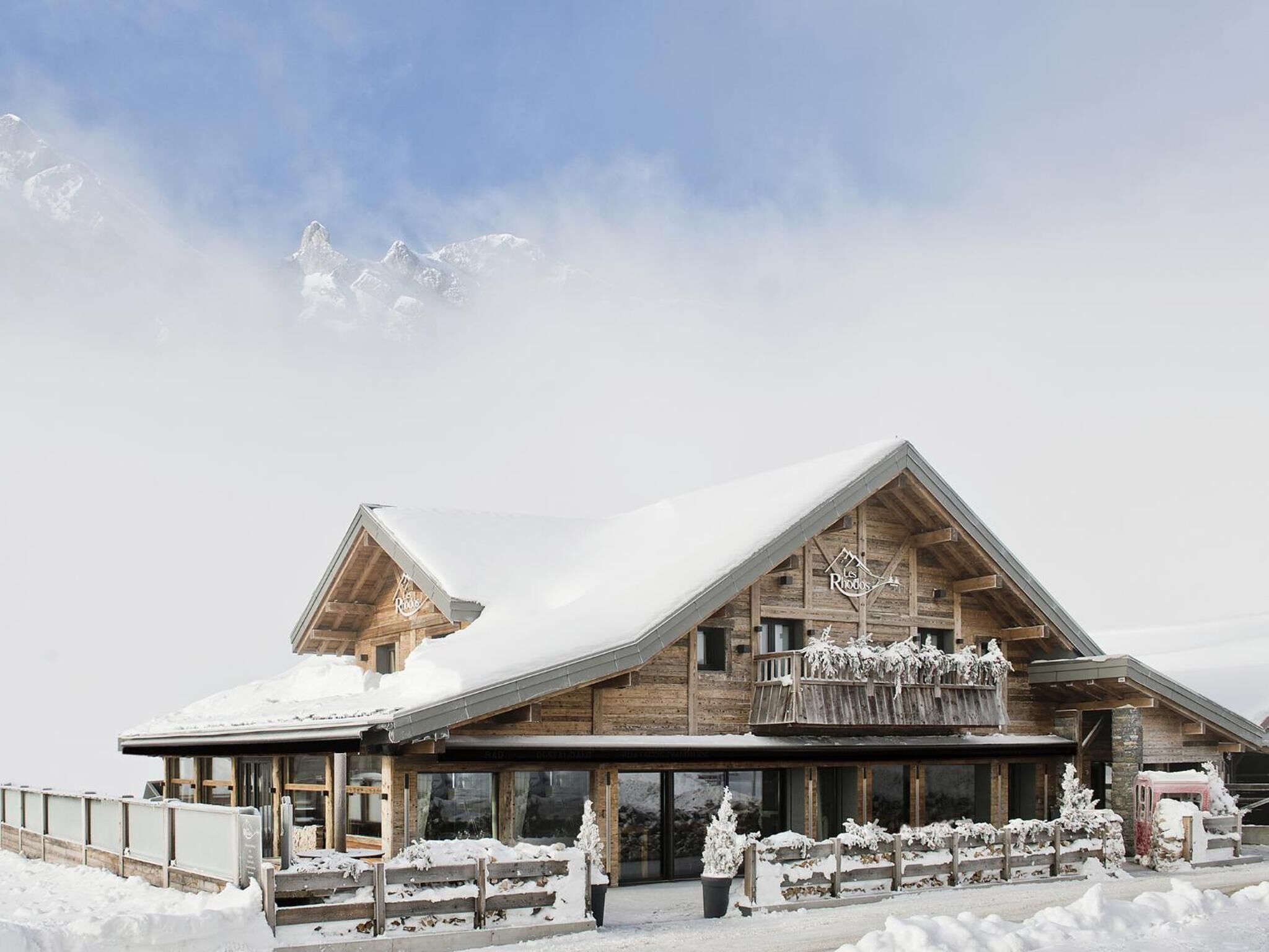 A wooden chalet with a sloped roof, large windows, and a balcony.