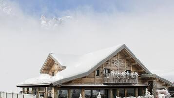A wooden chalet with a sloped roof, large windows, and a balcony.