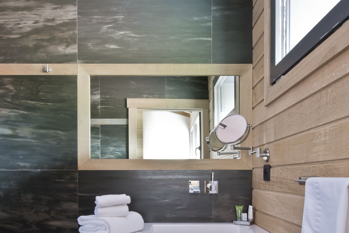 Un baño moderno con tocador de madera, un espejo grande y un perchero para toallas.