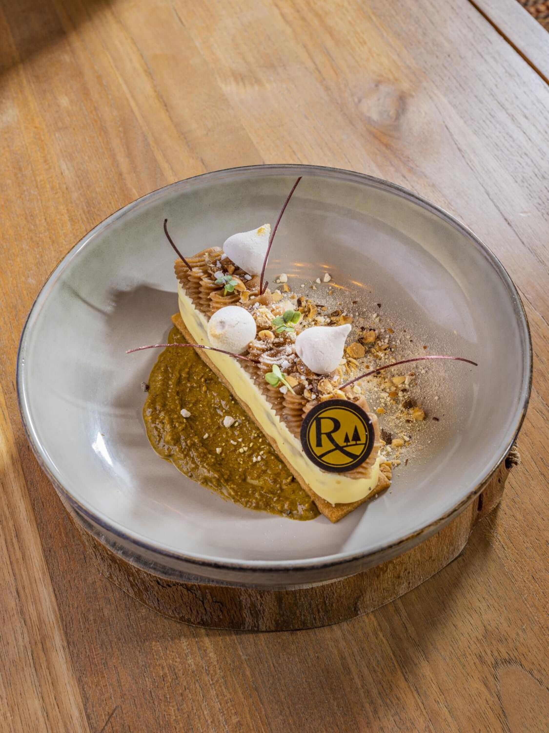 Un dessert présenté sur une assiette ornée d’un logo, posé sur une table en bois.