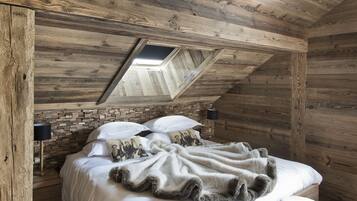 A wooden cabin bedroom with a loft bed, a skylight, and a rustic aesthetic.