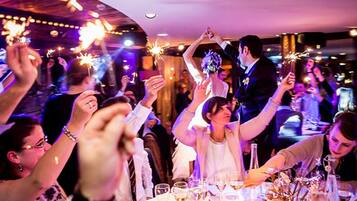 Een huwelijksreceptie met gasten die fakkelhouders vasthouden, een tafel gedekt met wijnglazen en een kaars op tafel.