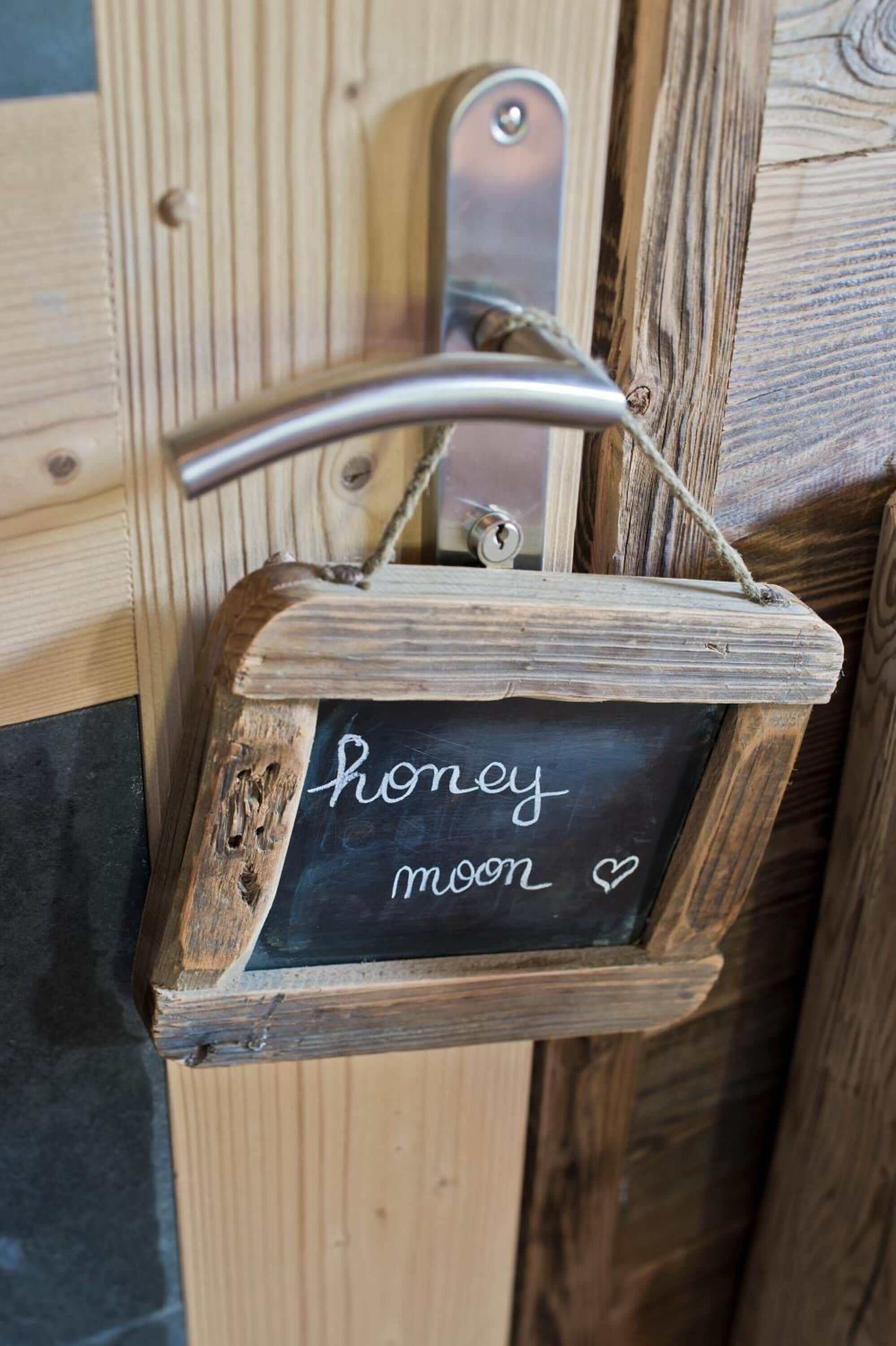 A rustic wooden sign with a metal handle, hanging on a wooden wall.