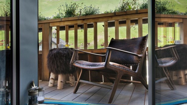 A balcony with a view of mountains, wooden chairs, and a striped rug. - Les Rhodos (La Clusaz)