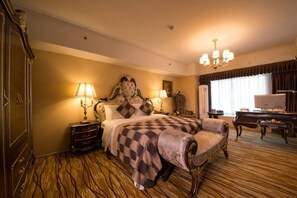 Une chambre spacieuse avec un grand lit, deux tables de chevet avec des lampes, un piano et une télévision.
