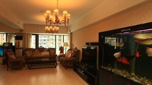 Una sala de estar con un pecera grande, suelo de madera y una araña.