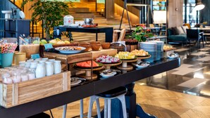 Ein reichhaltiges Buffet mit verschiedenen Speisen und Getränken, umgeben von Sitzgelegenheiten und einer Treppe im Hintergrund.