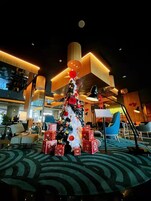 A hotel lobby with a decorated Christmas tree, seating areas, and modern lighting fixtures.