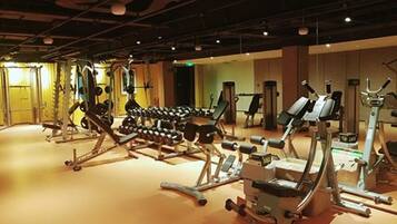 Un gimnasio con diverso equipo de ejercicios, incluyendo mancuernas, máquinas de pesas y máquinas de cardio.