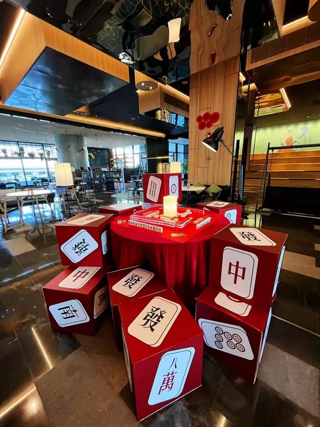A modern restaurant interior with a central round table displaying various dishes, surrounded by red boxes with Chinese characters.