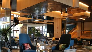 Eine moderne Lobby mit Sitzbereichen, einer Treppe und einem großen Fenster, das für natürliches Licht sorgt.