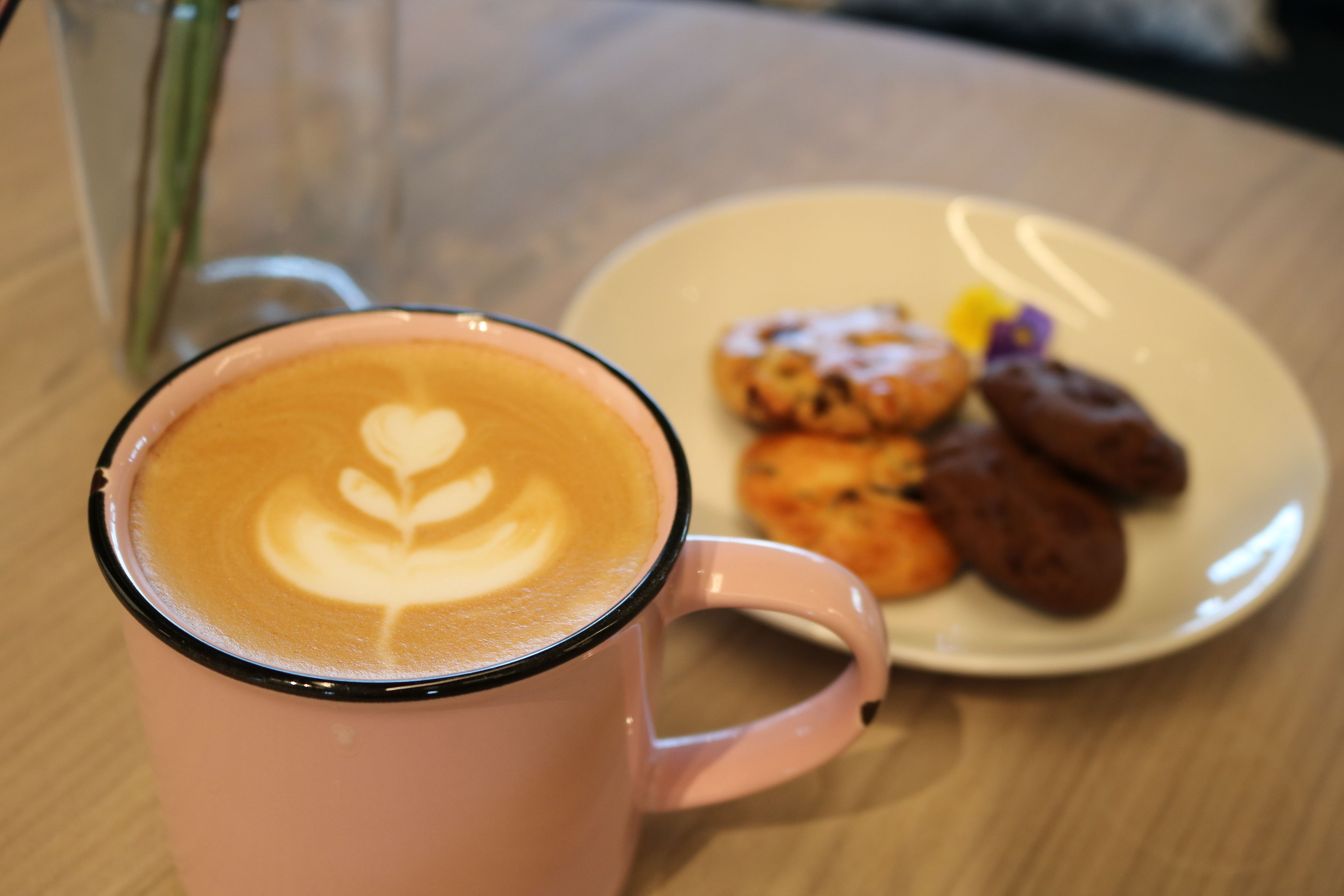 A pink mug with latte art on a table.