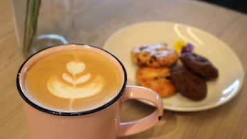 A pink mug with latte art on a table.