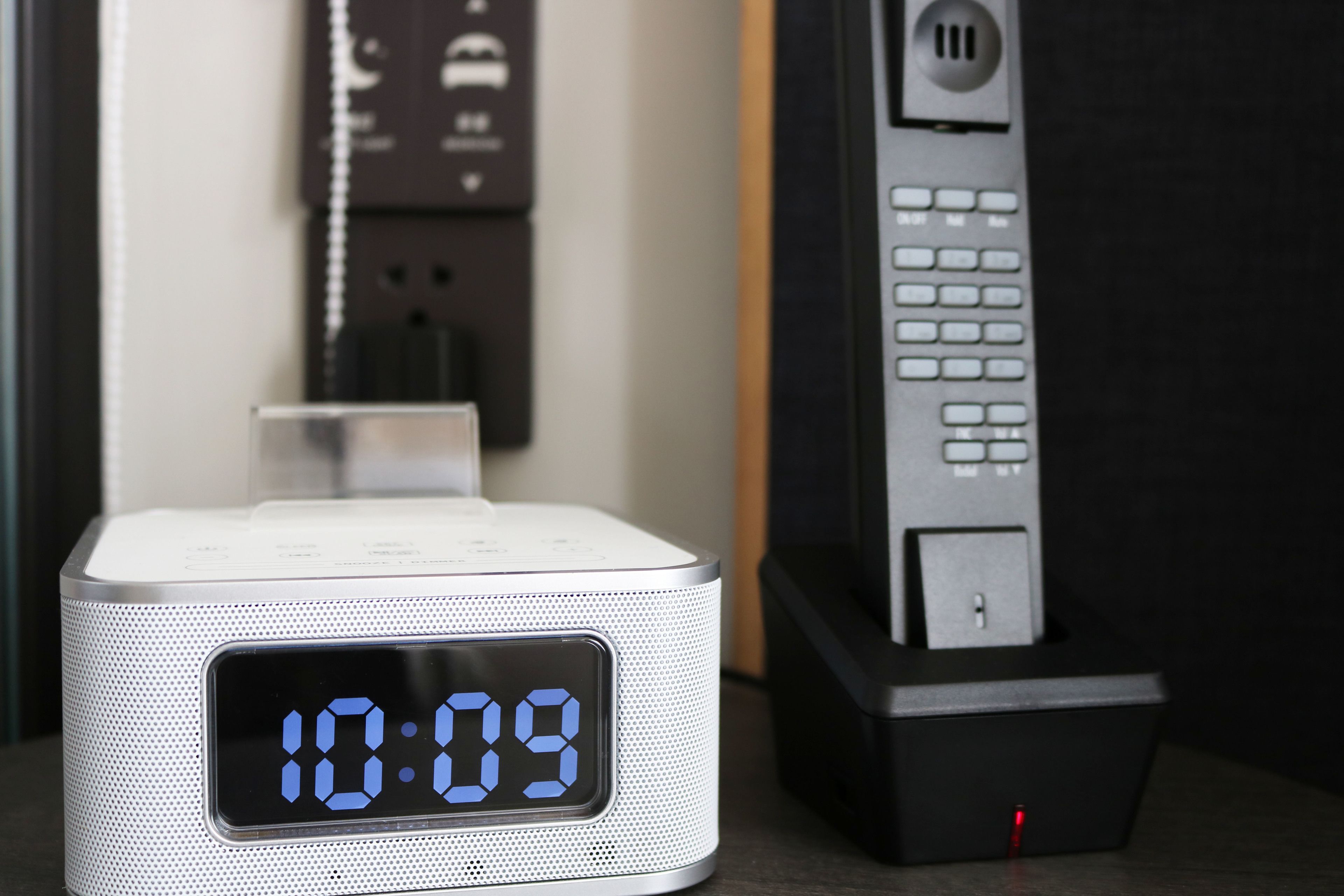 A digital clock displaying 10:09, a charging station, and a remote control.