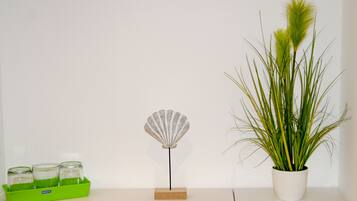 Una planta en test, una petxina decorativa i una safata verda amb gots sobre una superfície blanca.
