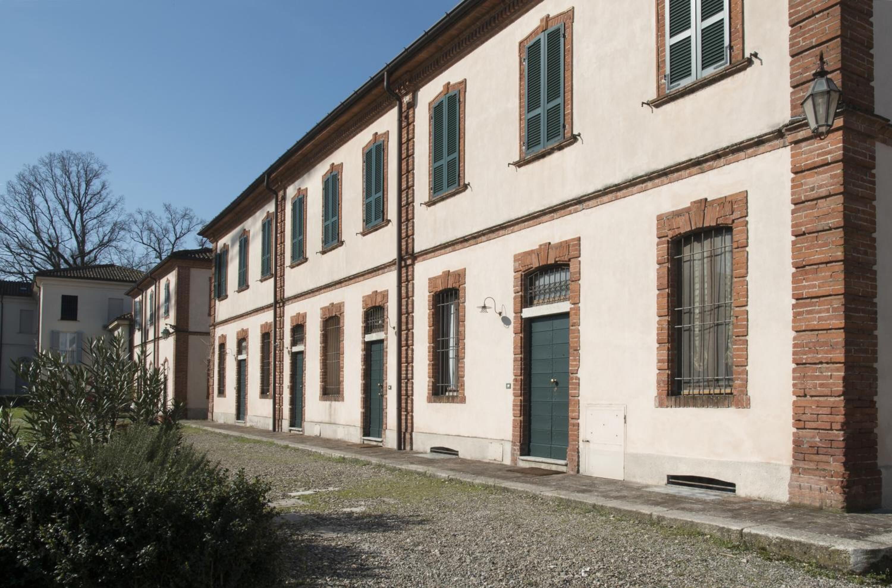 Una hilera de edificios de estilo arquitectónico uniforme, con fachadas de ladrillo y enlucido, contraventanas verdes y un camino de grava.