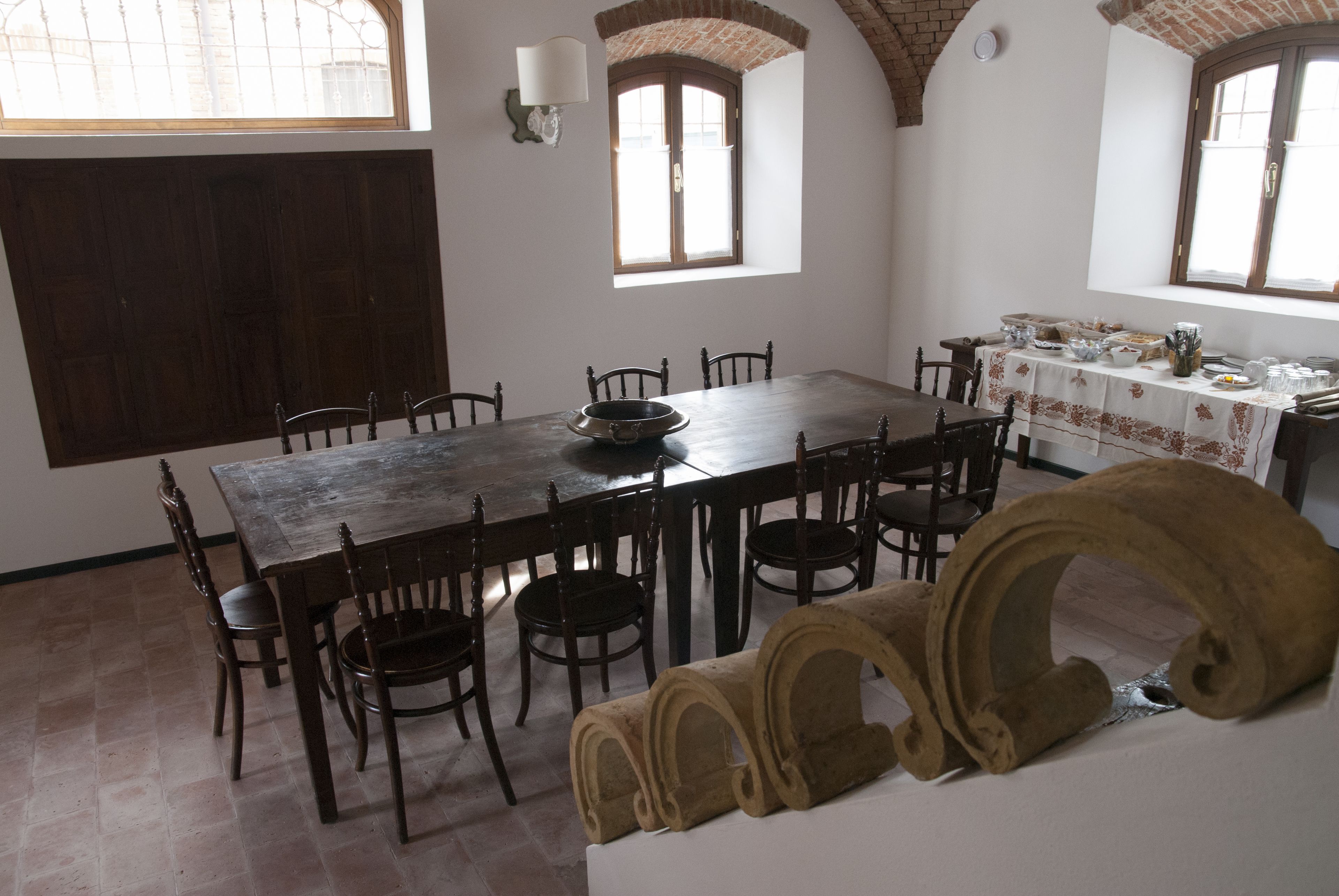 A dining area with a large wooden table, several chairs, and a window with a view.