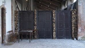 A rustic interior with wooden doors, a bench, and a table. - Palazzo Turro B&B (Podenzano)