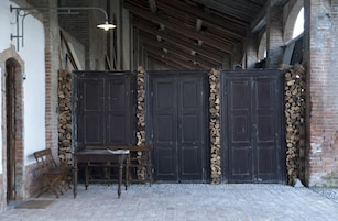 Un interior rústico con puertas de madera, un banco y una mesa.