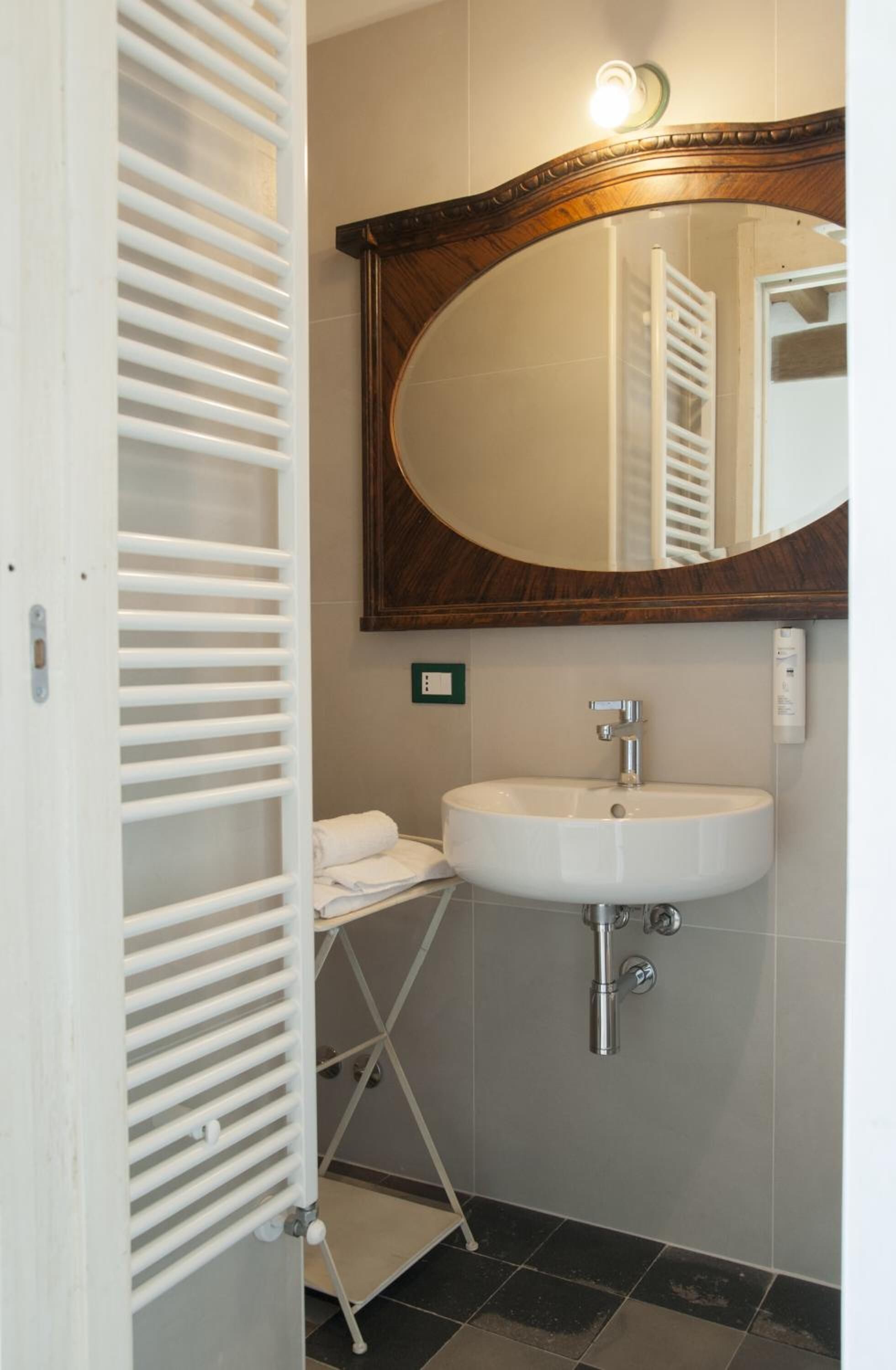 A bathroom with a white sink, a mirror with a wooden frame, and a towel rack.