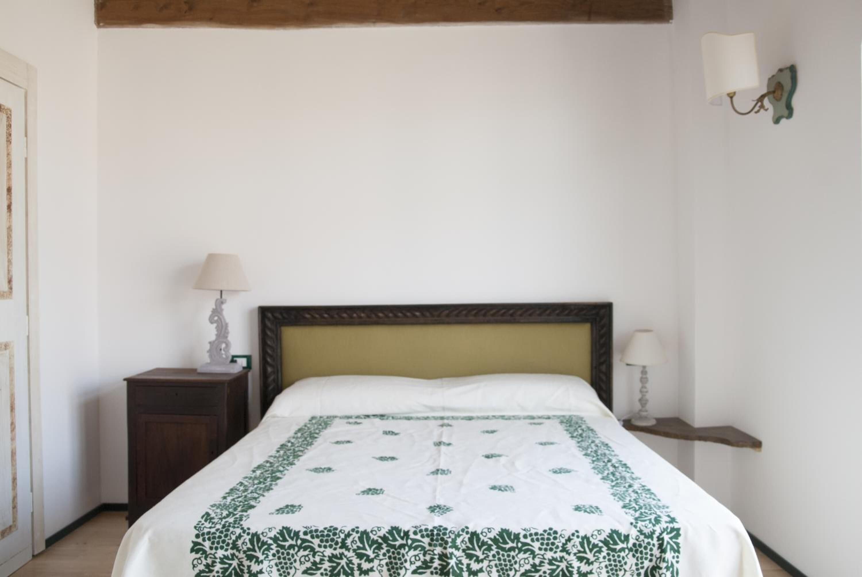 A bedroom with a bed, two bedside tables, and a wall-mounted lamp.