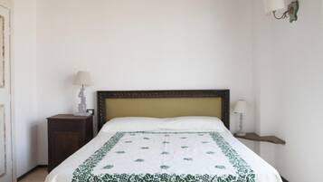 A bedroom with a bed, two bedside tables, and a wall-mounted lamp.