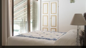 A bedroom with a bed, a nightstand, a lamp, and a window with a view of the outside. - Palazzo Turro B&B (Podenzano)