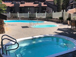 A swimming pool with a stone wall and a white fence.