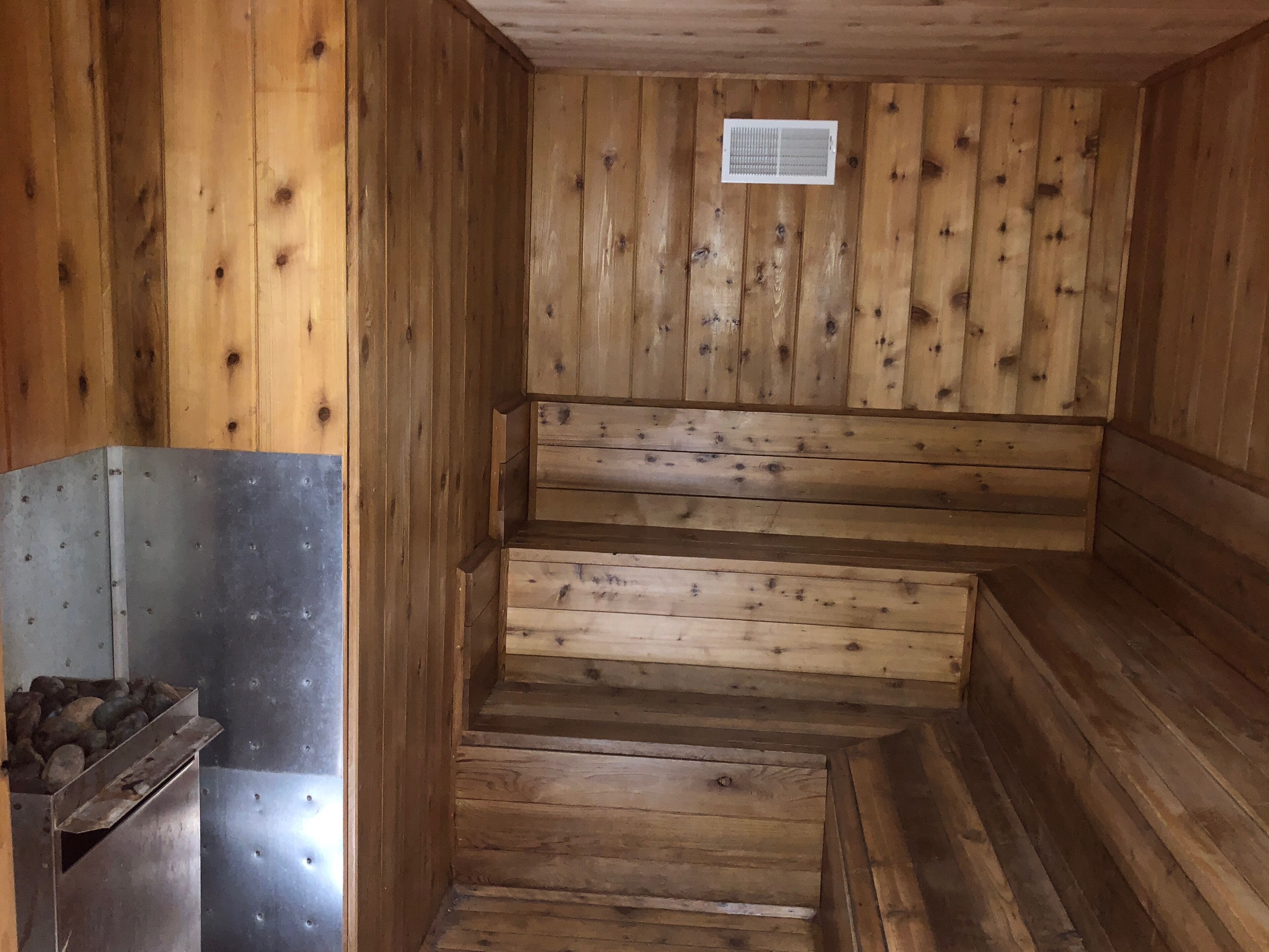 Un interior de madera con un banco de metal y una rejilla de ventilación.