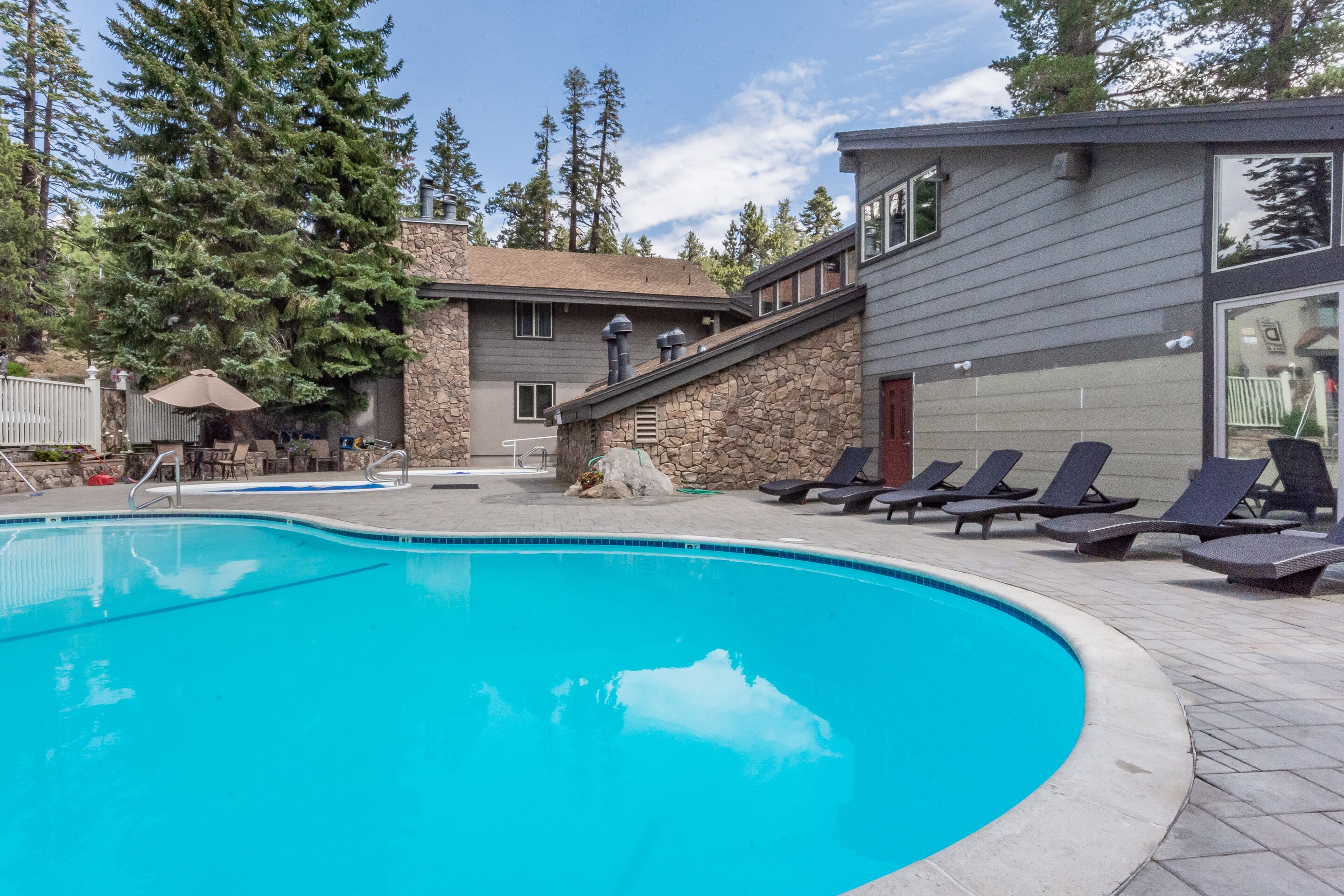 A swimming pool with lounge chairs and a stone building in the background.