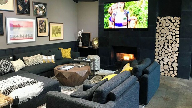 Una sala de estar moderna con chimenea, asientos cómodos y un televisor de pantalla plana montado en la pared.