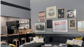 Una sala de estar moderna con sofás grises, una mesa de centro y una zona de cocina al fondo.