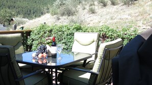 Un espace de restauration en plein air avec une table et des chaises, une bouteille de vin et un verre.