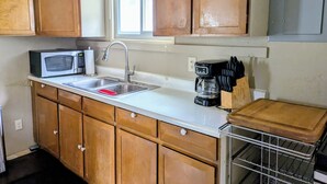 Une cuisine dotée de meubles en bois, d’un four à micro-ondes, d’un évier, d’une machine à café et d’un bloc à couteaux.