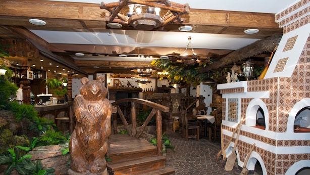 A rustic interior with wooden decor, a bear statue, and a thatched roof. - Egorkino Hotel (Astana)