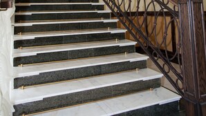 A staircase with marble steps and a wrought iron railing. - Egorkino Hotel (Astana)