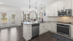 A modern kitchen with white cabinets, stainless steel appliances, and a large island.