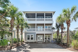 A two-story building with a balcony, surrounded by palm trees and a paved driveway.