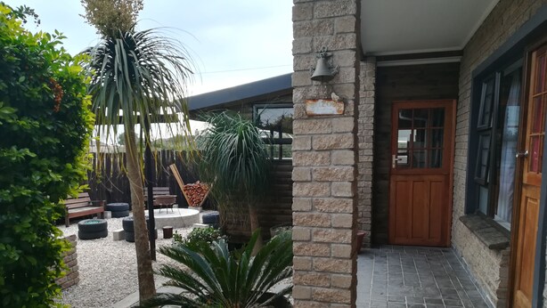 A courtyard with a wooden bench, a potted plant, and a stone wall.