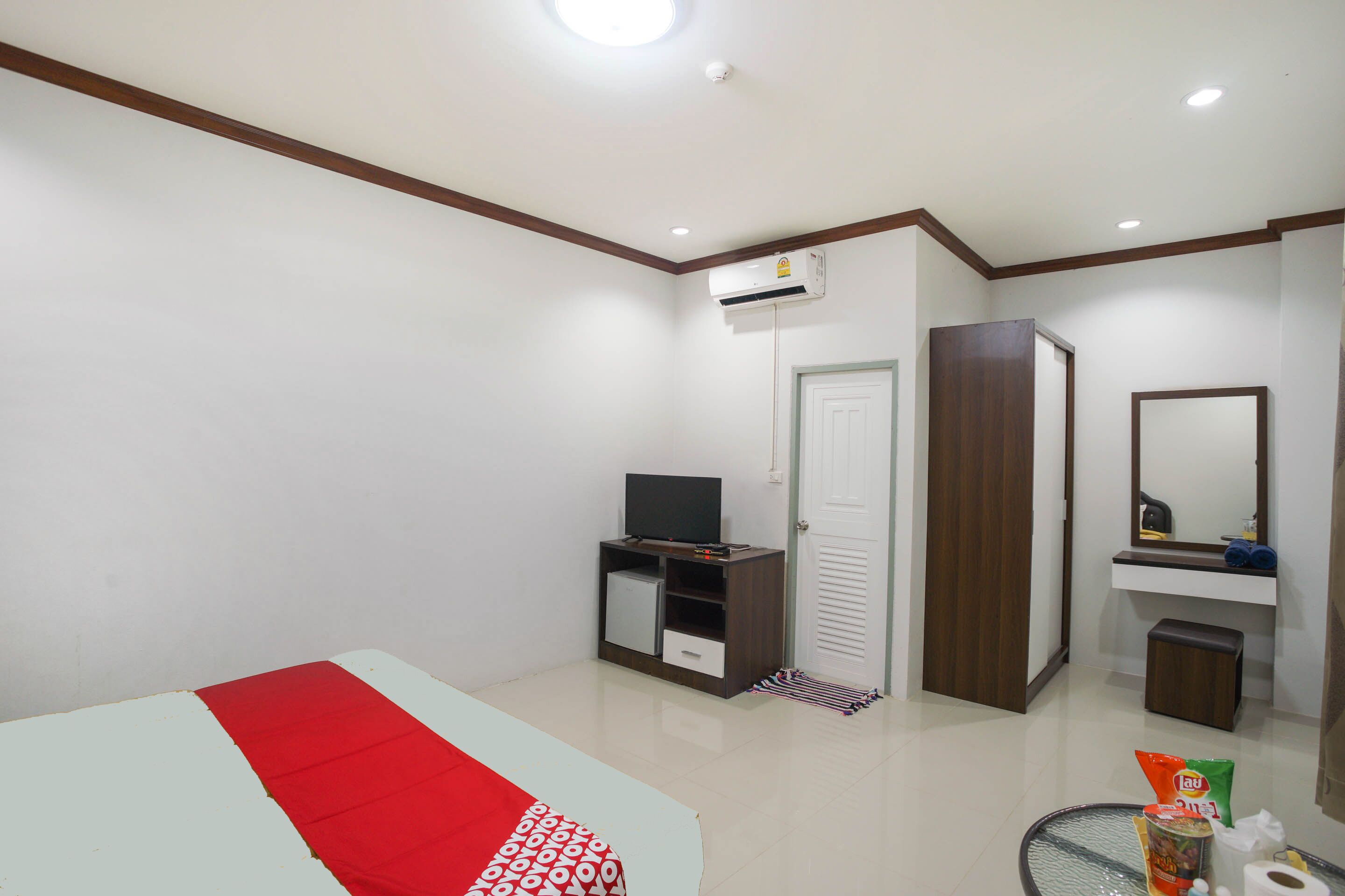 Une chambre à coucher comprenant un lit, une télévision, une armoire, un miroir et une salle de bain avec un lavabo et des toilettes.