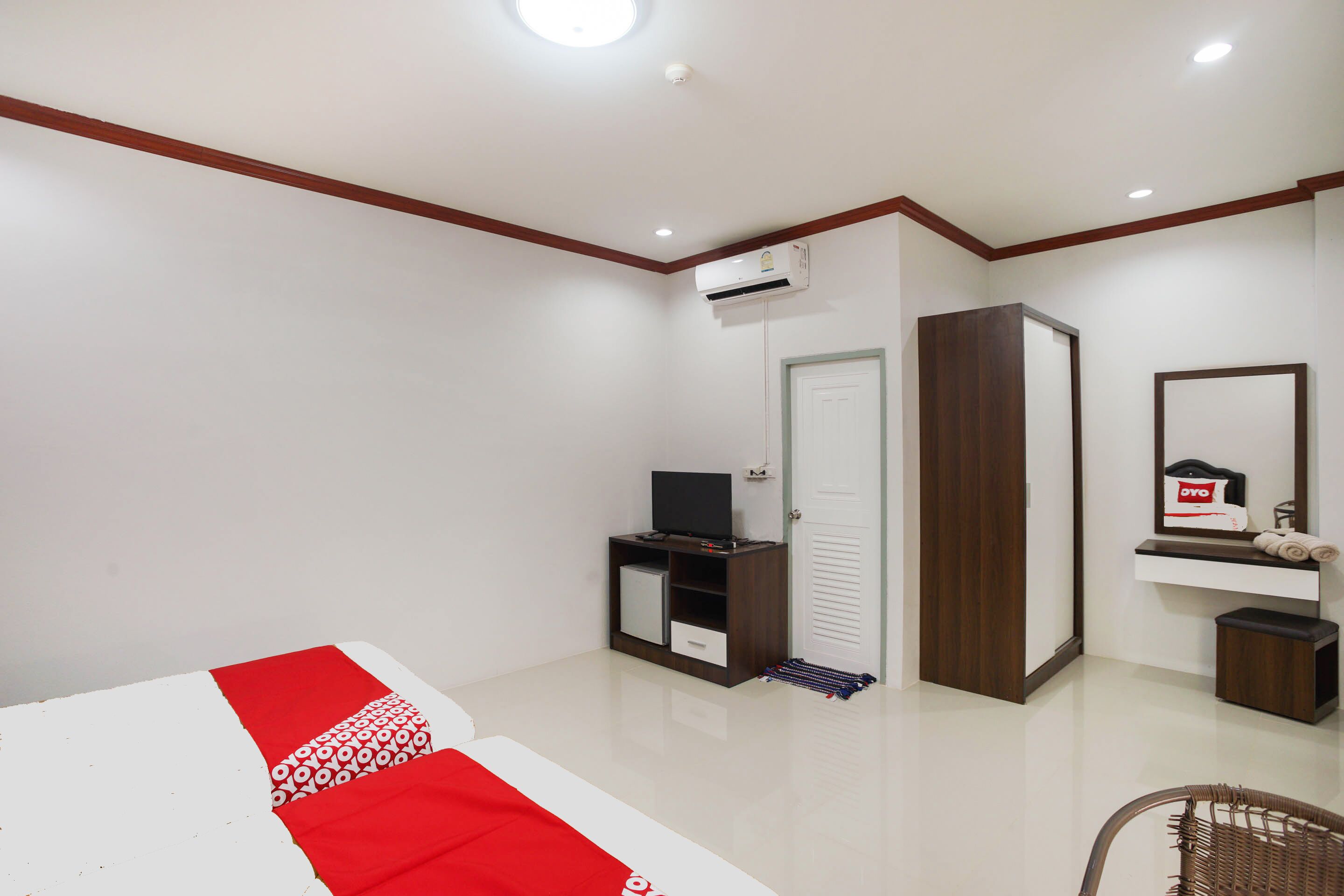 Un dormitorio con cama, televisión, armario, espejo y aire acondicionado.