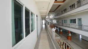 Een lange, smalle gang met meerdere verdiepingen, glazen balustrades en een centrale trap.