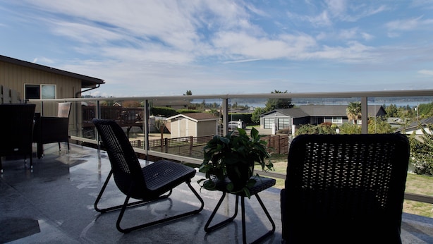 A balcony with two chairs, a small table, and a potted plant. - Scenic Lake View Home (Tacoma)