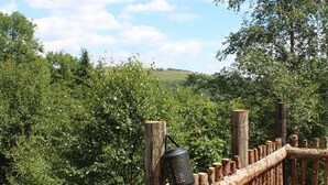 A wooden deck with a rustic railing, overlooking a lush green landscape. - Llethrau Farm (Knighton)