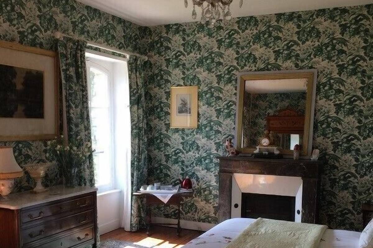 Une chambre à coucher avec un lit, une commode, un miroir et un lustre.