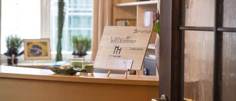 A reception area with a wooden counter, a welcome sign, and a door.