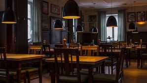 A restaurant with wooden tables and chairs, pendant lighting, and framed artwork on the walls. - Mettner Hof (Metten)